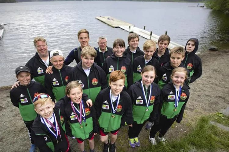 Unge roere med medaljer samlet på stranden ved brygga